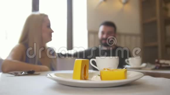 甜蜜的甜点在一对夫妇面前坐在咖啡馆里享受咖啡笑着视频的预览图