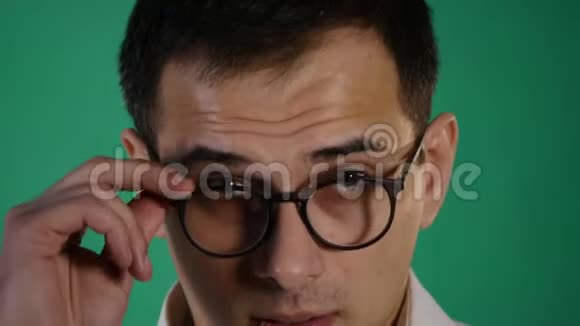 特写一幅令人感兴趣的目瞪口呆的男性看着摄像机下巴掉了出来碰了碰眼镜被隔离在绿色上视频的预览图