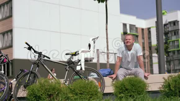 现代生活在一个大城市运动的年轻人在骑自行车后在城市的长凳上休息视频的预览图