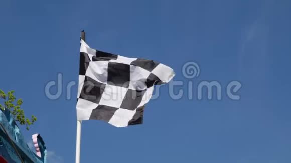 格子的赛车旗在蓝天背景下在空中摇动视频的预览图