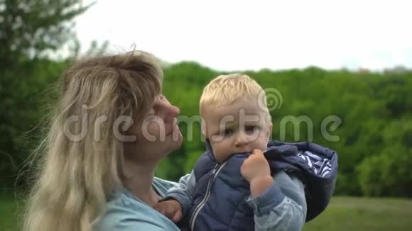 快乐的年轻金发母亲抱着她的孩子在公园散步视频的预览图