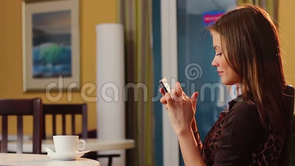 漂亮的女士坐在咖啡馆里喝咖啡时会发电话视频的预览图