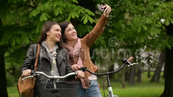 有魅力的女性自行车手在春天的时候在公园里用智能手机户外拍照二视频的预览图