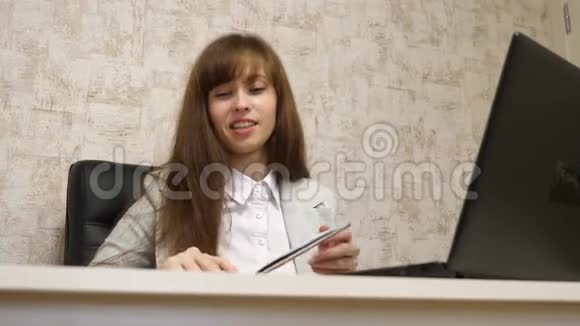 漂亮的女孩坐在办公室的椅子上用bloknot说话和做笔记青年女企业家视频的预览图
