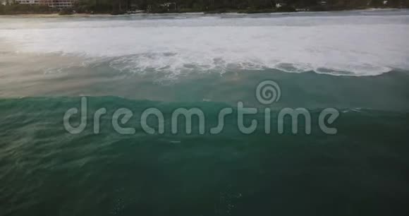 无人机照相机跟随巨大的蓝色海洋泡沫波冲到美丽的异国度假胜地海岸与热带树木和房屋视频的预览图