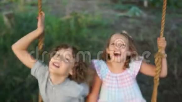 姐姐和哥哥在花园里骑着秋千孩子们胡闹建立面孔快乐的童年暑假视频的预览图
