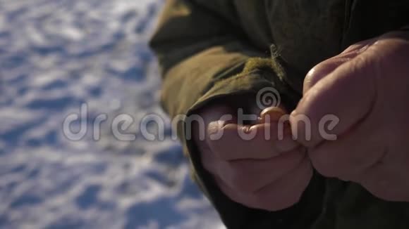 一位老人把鱼钩挂在钓鱼钩上冬季捕鱼4K视频的预览图