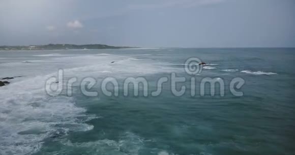 戏剧性的无人机拍摄的大泡沫海波在多云的暴风雨天空下撞击在异国热带海岸附近的凯伊石视频的预览图