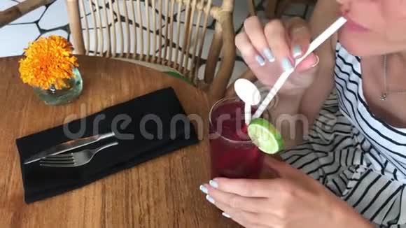 年轻女子在印度尼西亚巴厘岛的餐厅喝红鸡尾酒4K镜头视频的预览图