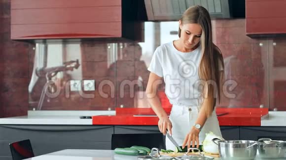 漂亮的年轻女人在厨房里切东西视频的预览图