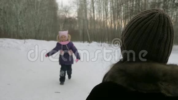 女孩跑到妈妈身边在冬天的森林里拥抱她视频的预览图