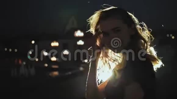 女孩肖像剪影头发在微风中挥动在夜间城市背景城市灯光中的轻发火灾视频的预览图