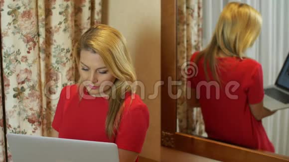 思考女人看着笔记本电脑站在镜子后面视频的预览图