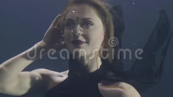 一位穿着黑色裙子在黑暗背景下水下游泳的美女视频的预览图