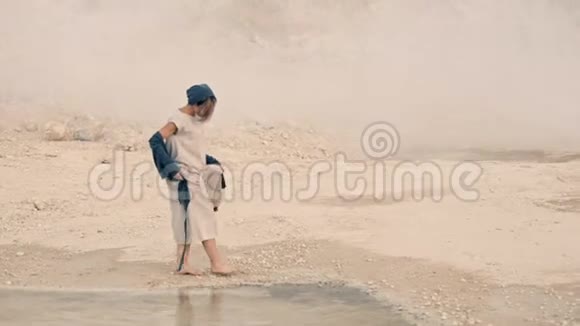 年轻女子在山和雾的背景下沿着湖的岸边走视频的预览图