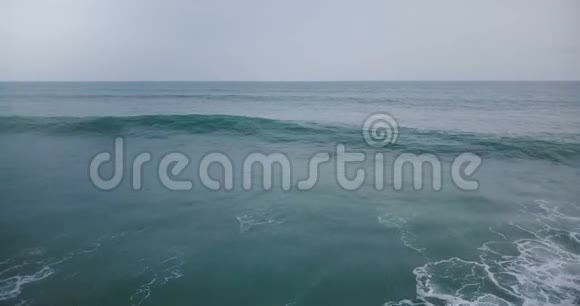 空中无人驾驶飞机飞越大海浪撞击白色泡沫在惊人的深蓝色开阔的海洋和天际线视频的预览图