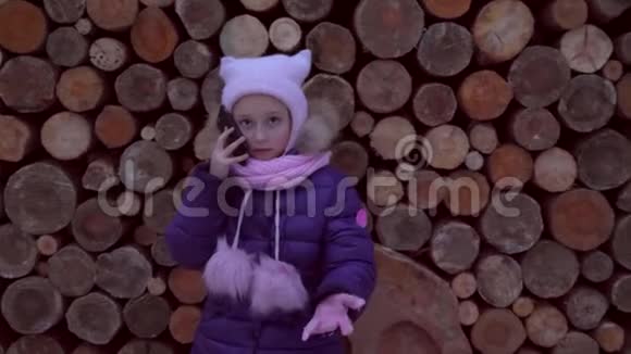 在木头纹理背景上用手机说话的愤怒小女孩视频的预览图