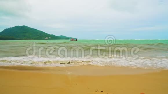 在多云的天气里海岸上有强烈的波浪在暴风雨沙滩地平线上的一个岛屿面前视频的预览图