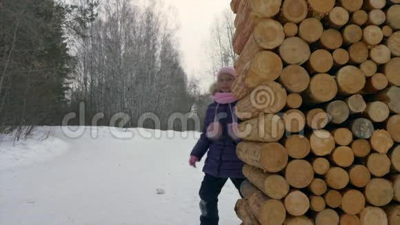 在冬天的森林里快乐的女孩从树上窥视玩捉迷藏视频的预览图