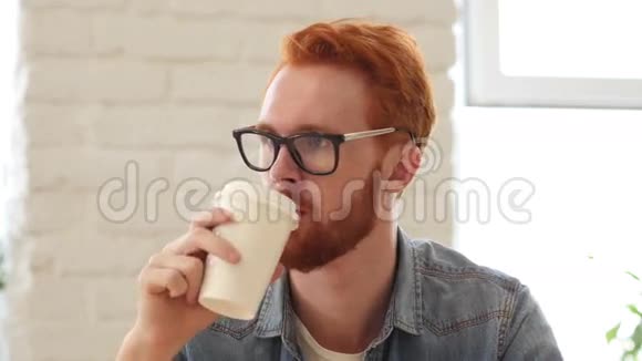 有胡子和红发的男人喝咖啡办公室喝茶肖像画视频的预览图