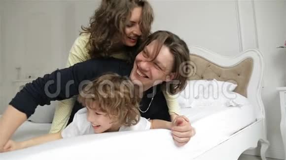 在卧室里和孩子们一起玩的年轻夫妇有两个孩子的漂亮丈夫和妻子视频的预览图