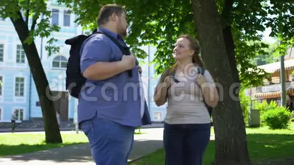 肥胖的大学生交谈和微笑公园里的浪漫约会友谊视频的预览图