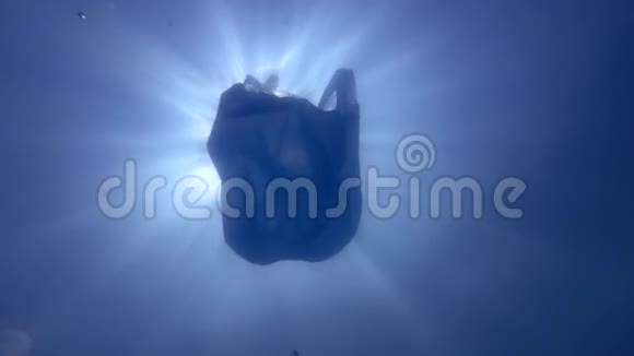 塑料污染一个废弃的蓝色塑料袋在阳光下慢慢漂浮在水下表面水下射击低角度射击视频的预览图