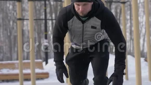 在寒冷的天气里在冬季运动场上用健身扩张器进行强壮的男子训练视频的预览图