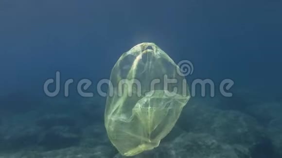 塑料污染蓝色水中黄色塑料袋废弃的塑料袋在阳光下慢慢地漂浮在蓝色的水面下视频的预览图