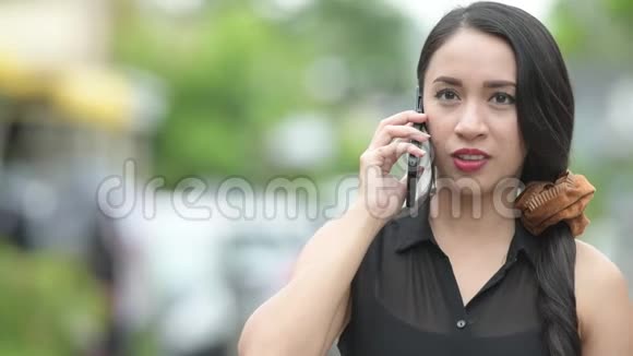 年轻漂亮的亚洲女商人在户外大街上打电话视频的预览图