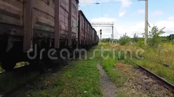 在货运列车底盘附近的旧火车站4K走在长满草的车辙上视频的预览图