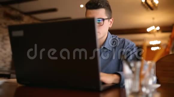 英俊的自由职业者戴眼镜的商人努力在咖啡馆的笔记本电脑上工作然后喝一杯咖啡男子视频的预览图