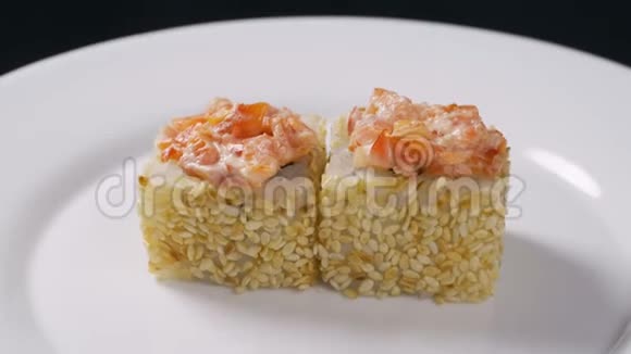 寿司卷日本食品旋转在黑色背景寿司卷配三文鱼豆腐蔬菜和鳄梨特写视频的预览图