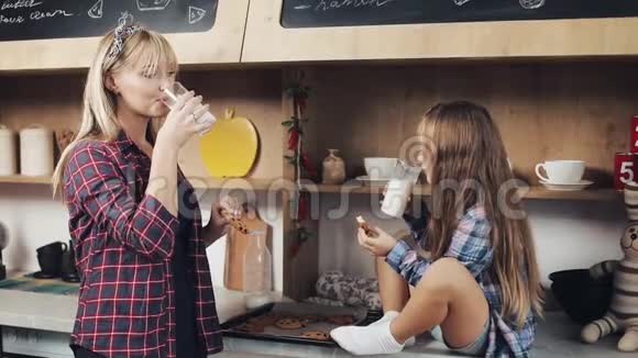 家庭幸福小女孩和妈妈一起在厨房吃牛奶和饼干钙早餐健康慢动作视频的预览图