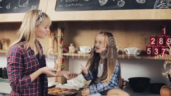 家庭幸福小女孩和妈妈一起在厨房吃牛奶和饼干钙早餐健康慢动作视频的预览图