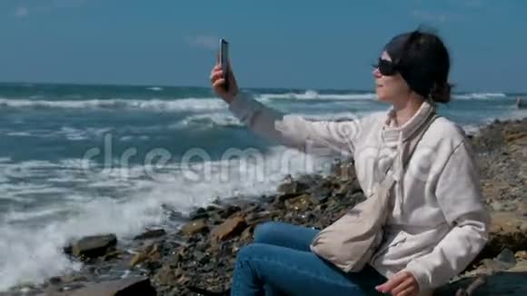 秋天女人在石滩上坐在海边自拍视频的预览图