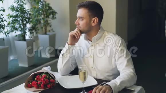 紧张的男人独自坐在餐厅的餐桌旁喝着香槟等着他的女朋友然后离开视频的预览图