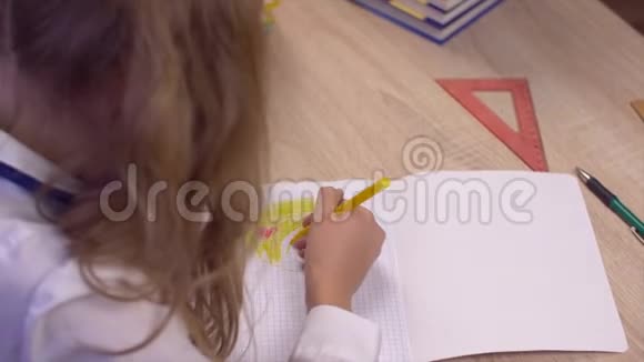 学校里的小女孩在桌上用彩色铅笔在笔记本上画画视频的预览图