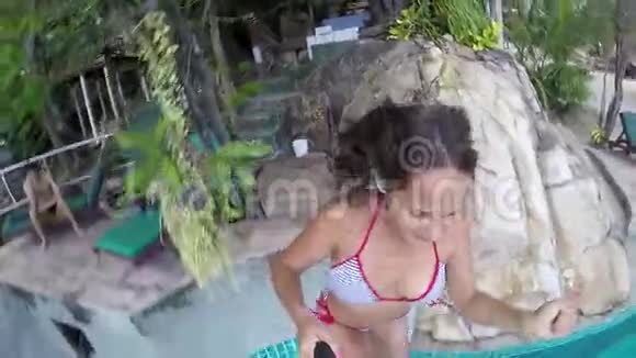 迷人的年轻快乐的女人在游泳池里用Gopro相机跳跃慢动作1920x1080视频的预览图