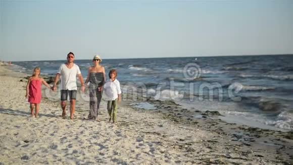 在海滨度假期间四位快乐家庭成员在海滩散步的正面景观视频的预览图
