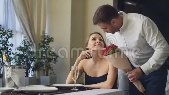 美丽的女人在餐馆等她的男朋友他来给她送花吻她快乐女孩视频的预览图