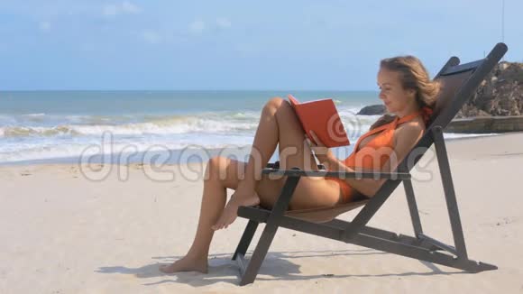 穿着泳装的女孩阅读反海浪书视频的预览图