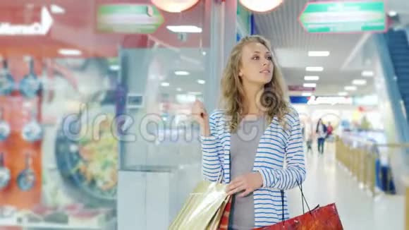 stadicam射击漂亮的年轻女子带着许多购物袋沿着商店购物中心走视频的预览图