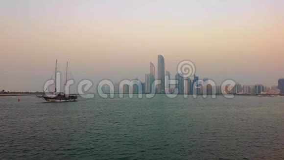 美丽的阿布扎比城市天际线塔和海滩日落大木船在海滩视频的预览图