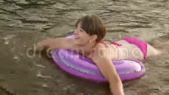 穿着泳衣的女孩在救生圈的水面上漂浮着笑了起来海滩季节视频的预览图