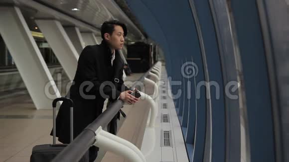 年轻的韩国商人使用电话站在机场大楼室内视频的预览图