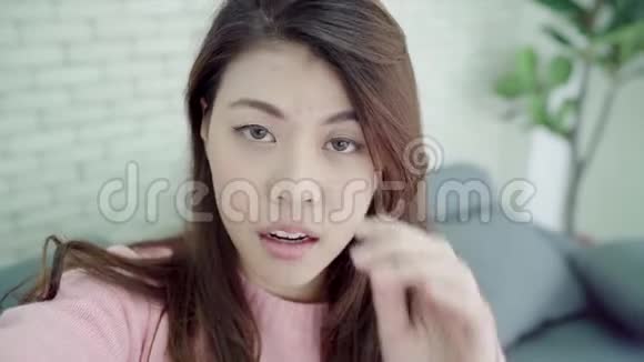 亚洲博客女性使用智能手机录制vlog视频在家客厅女性享受有趣的时刻视频的预览图