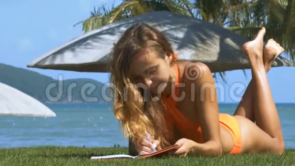 漂亮的女士在草坪上用钢笔书写视频的预览图
