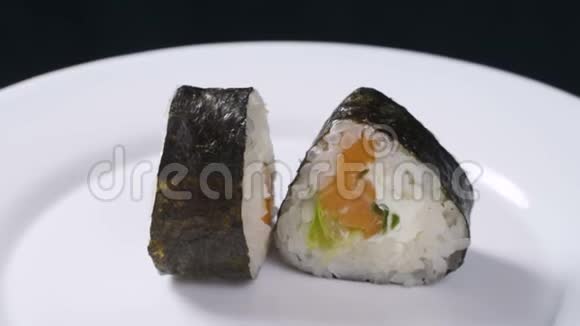 寿司卷日本食品旋转在黑色背景寿司卷配三文鱼豆腐蔬菜和鳄梨特写视频的预览图