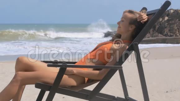 在沙滩木椅上放松欢乐的女人视频的预览图